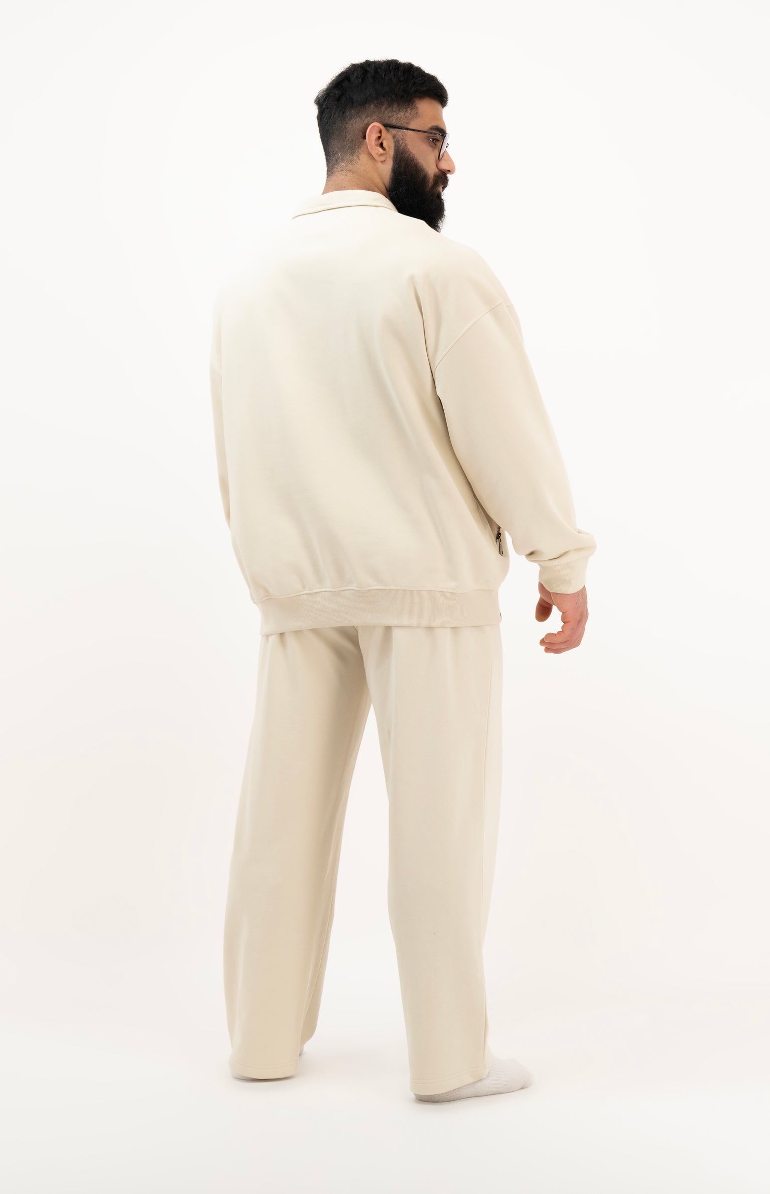Man wearing a beige tracksuit on a white background