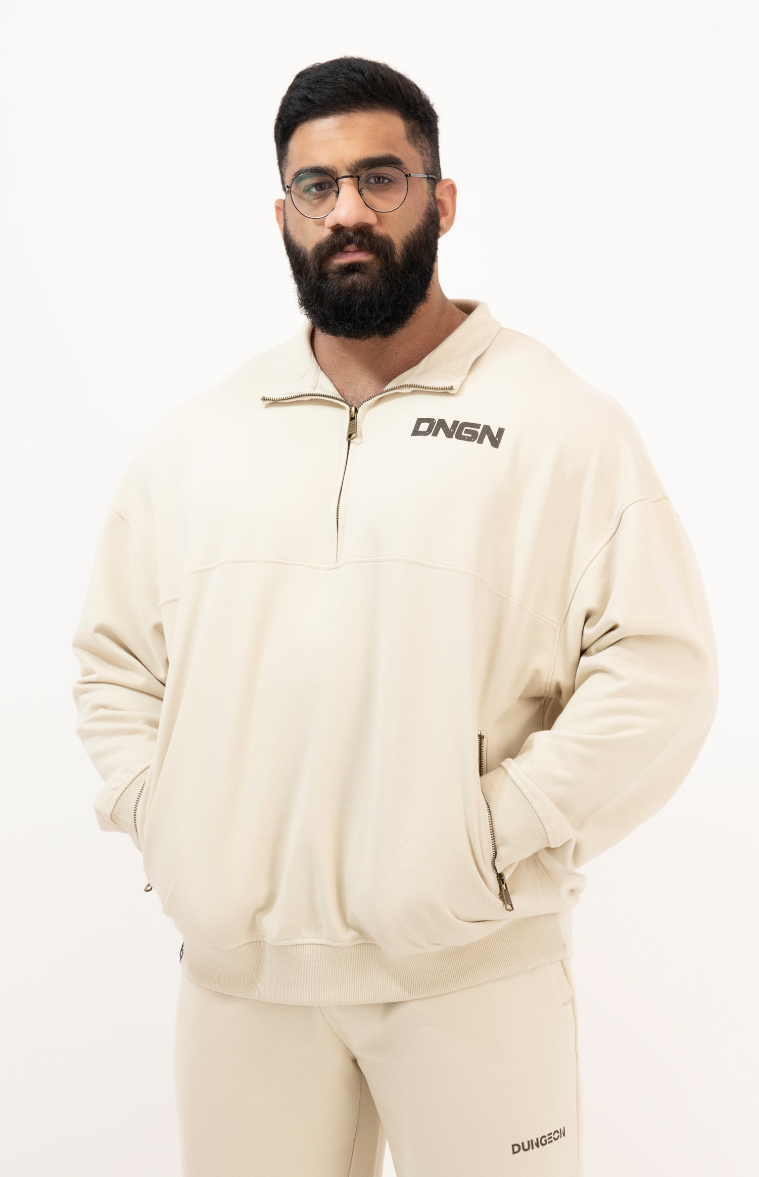 Man wearing a beige tracksuit with 'DKNY' branding on a white background