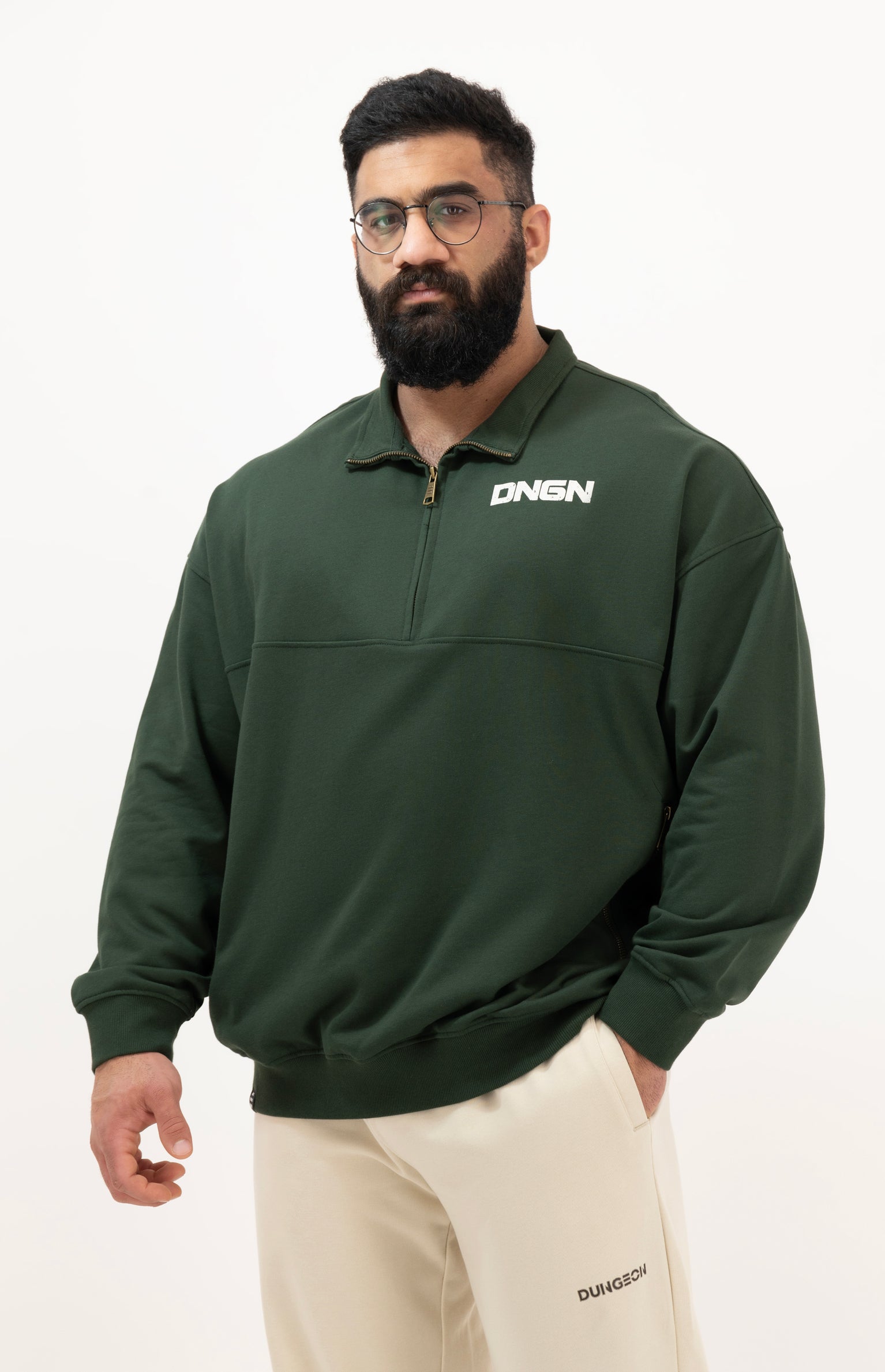 Man wearing a green pullover with a brand logo on a white background